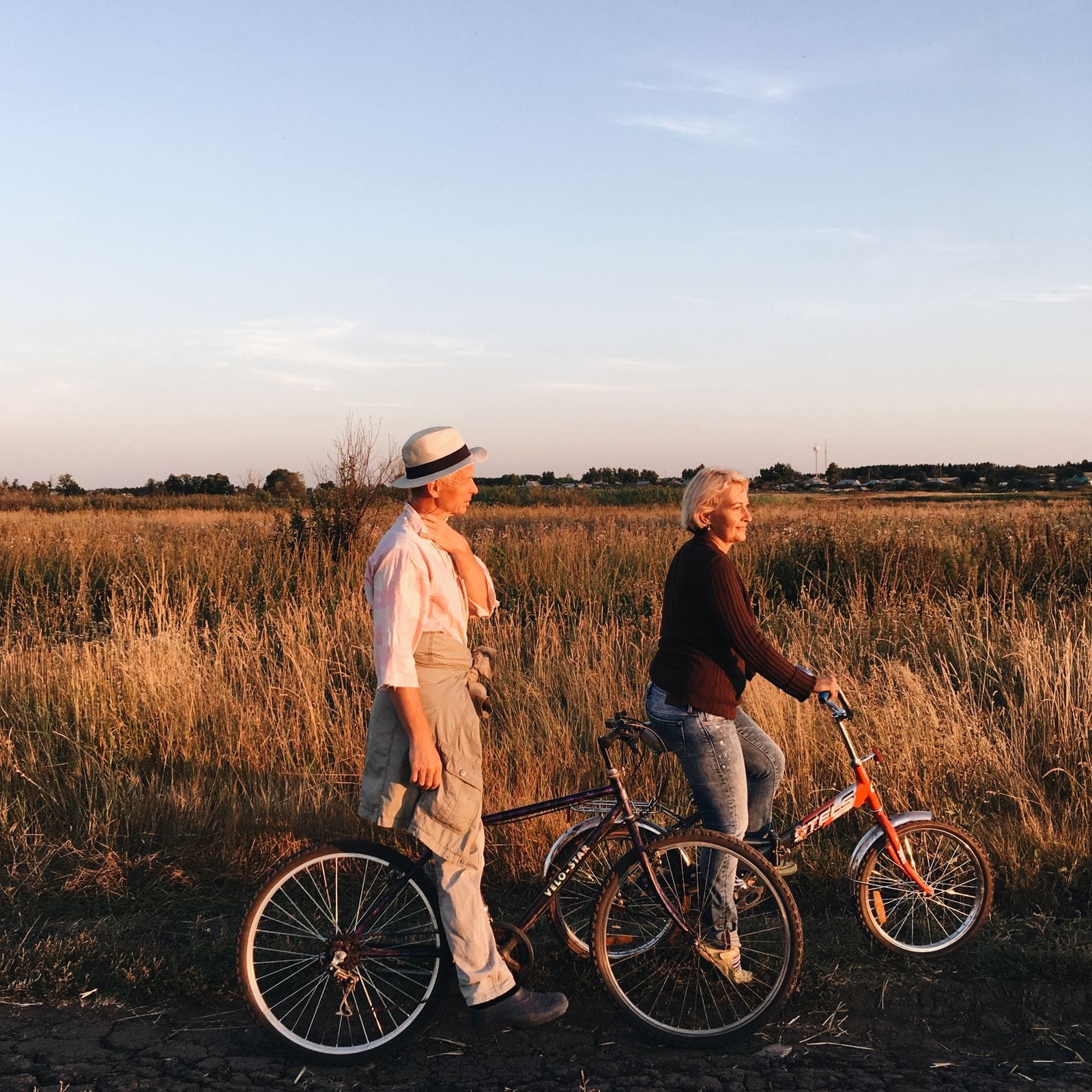 Ouder stel fietst samen door een grasveld in het avondlicht, inspiratie voor een fietsvakantie langs Duitse routes